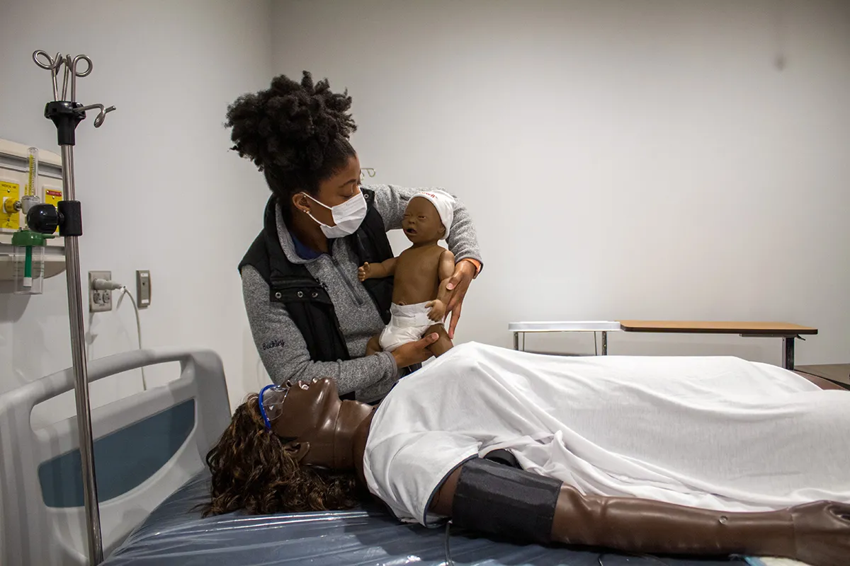 Student holding a baby dall