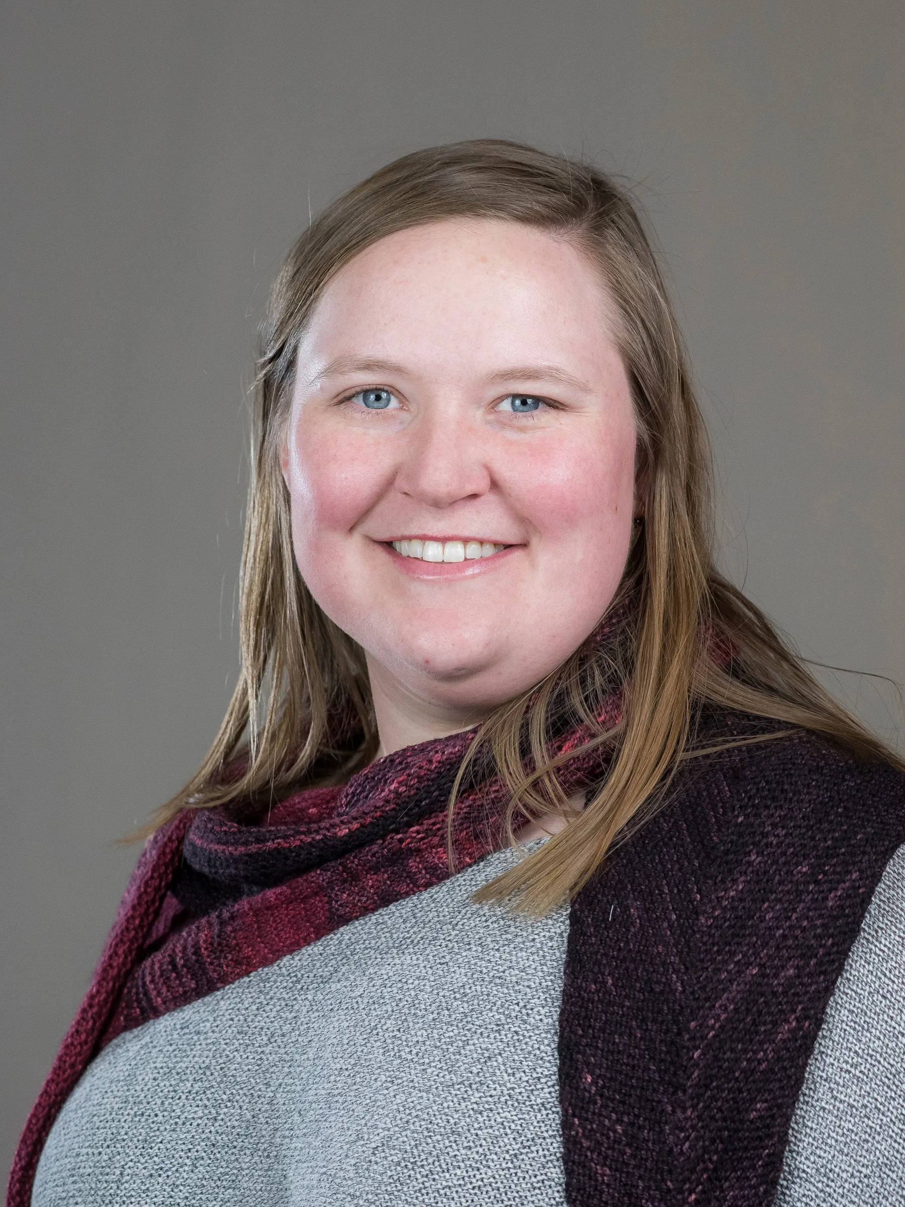Image of blonde woman in gray sweater with red scarf
