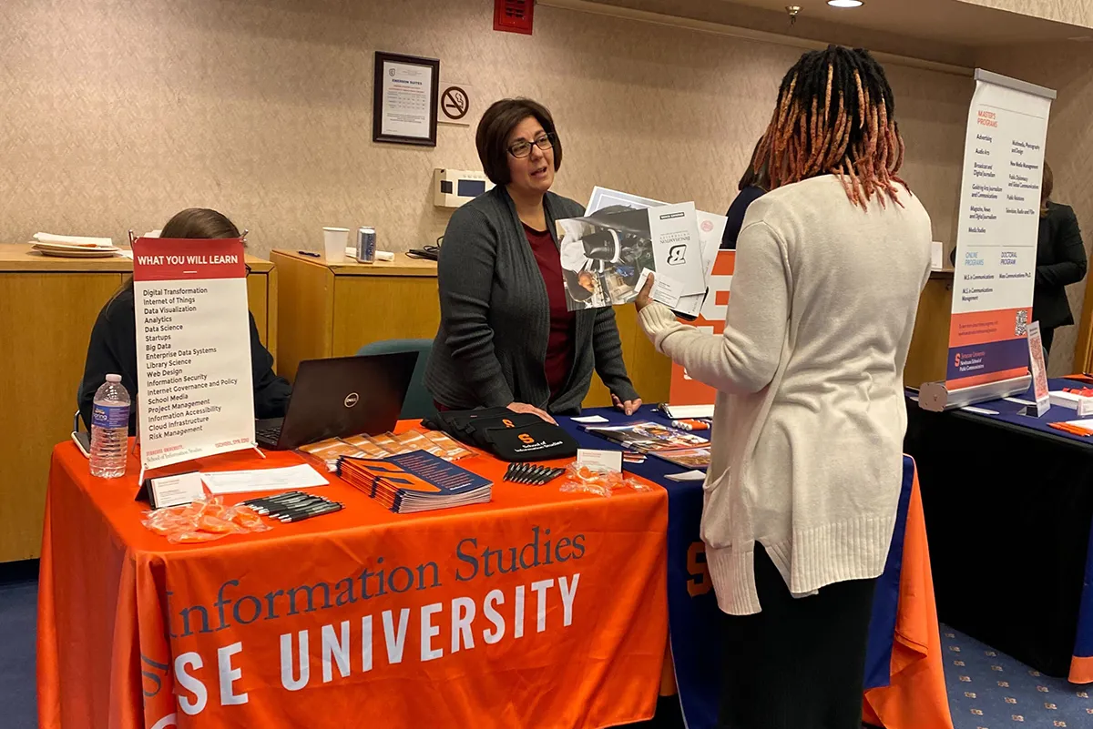 Student talking with a woman at a table