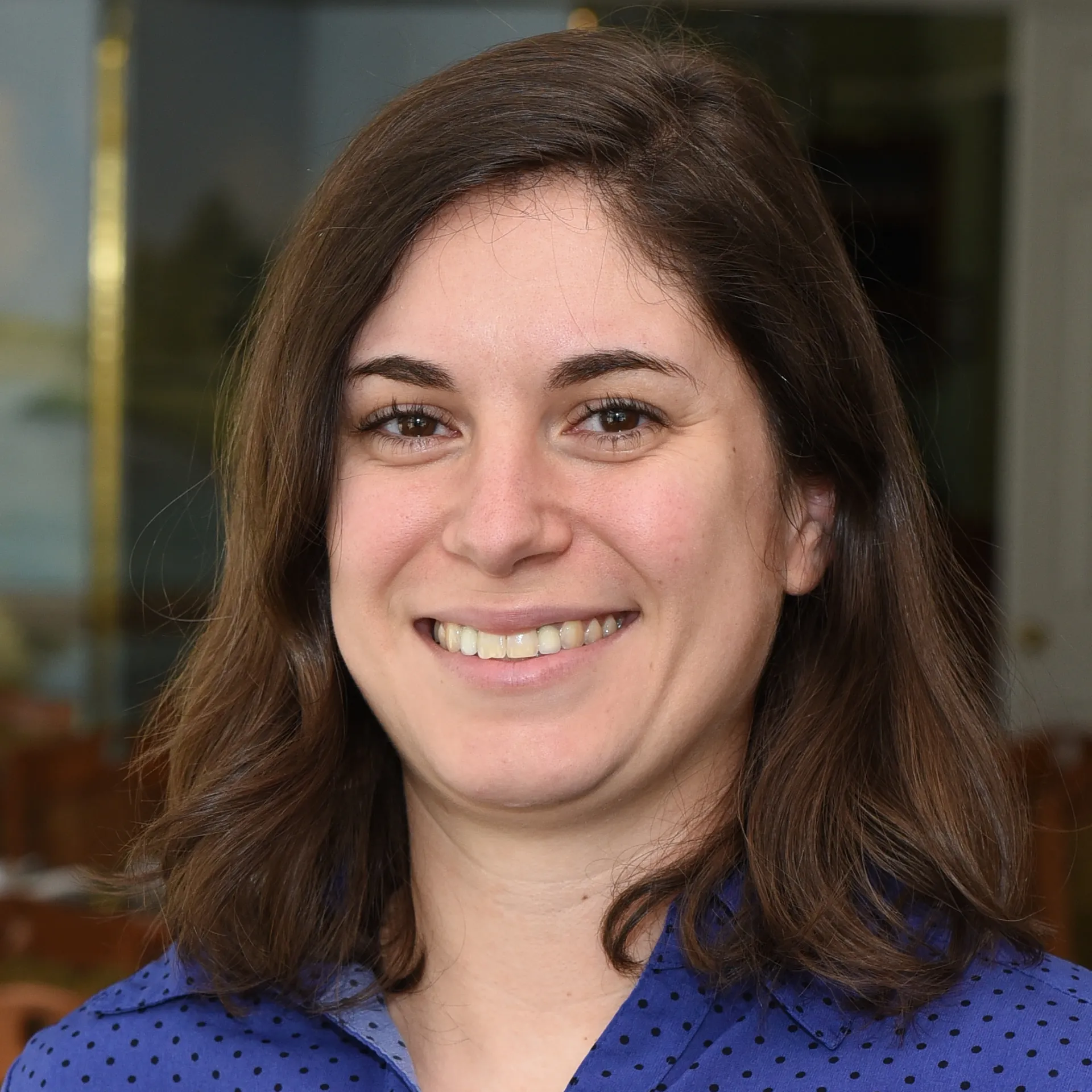A headshot of a woman wearing a purple polka-dotted shirt.