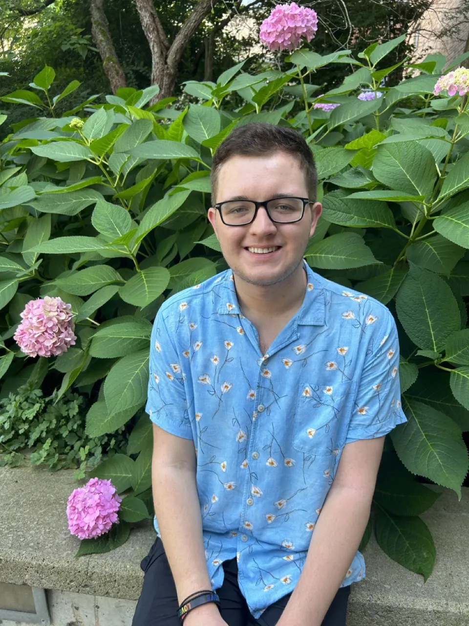 Person sitting in front of bush smiling