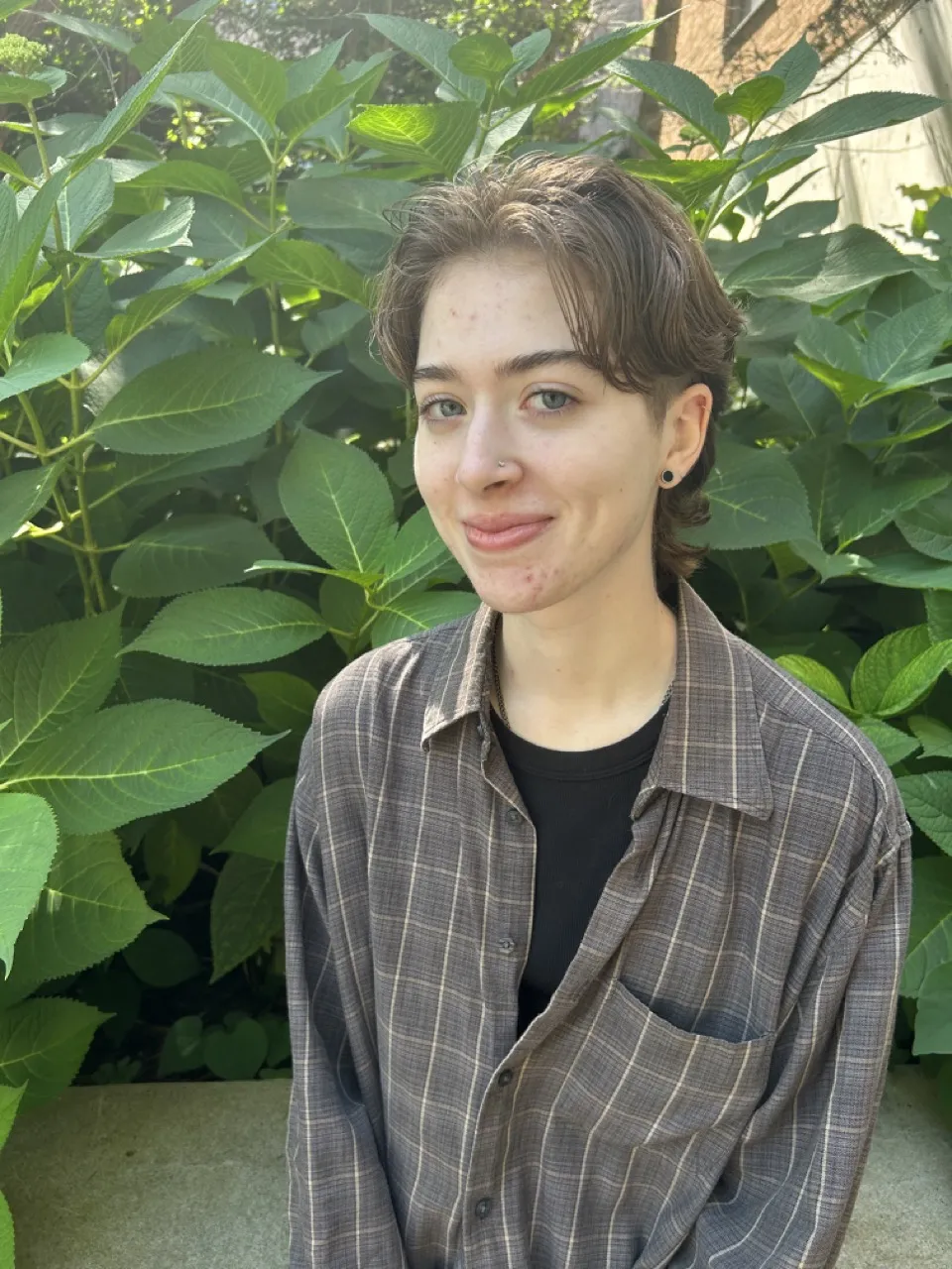 Person sitting in front of bush smiling