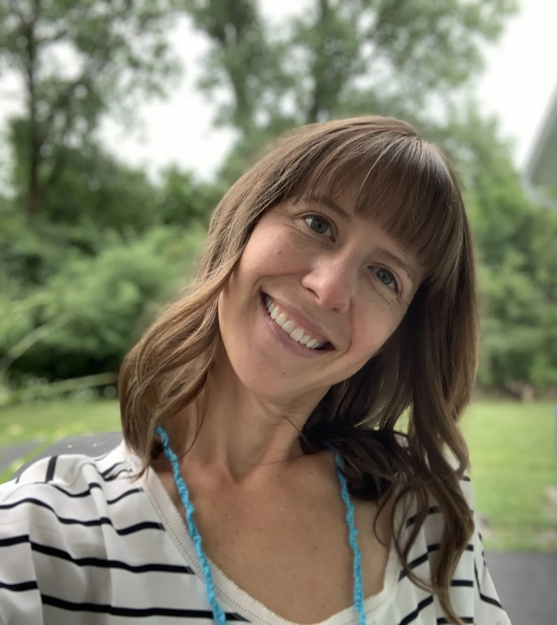 white female with brown hair smiling and tilting head outside