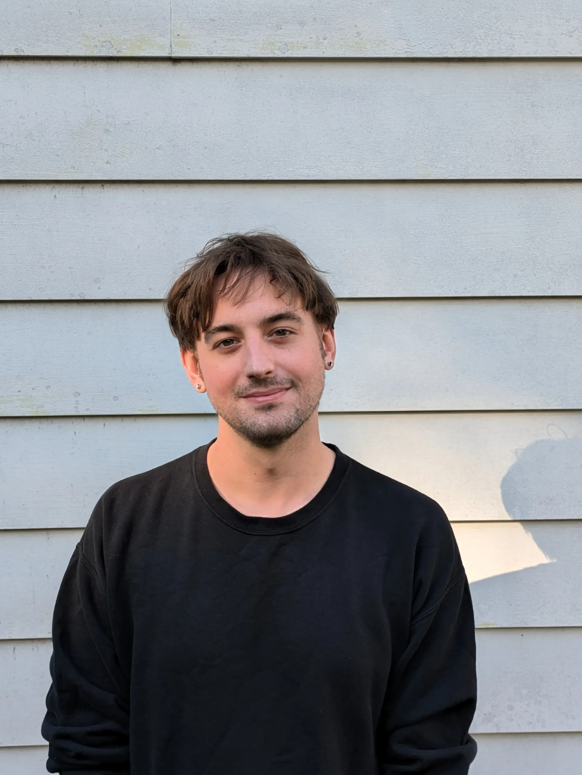 Professional headshot of white man in black sweater smiling at the camera
