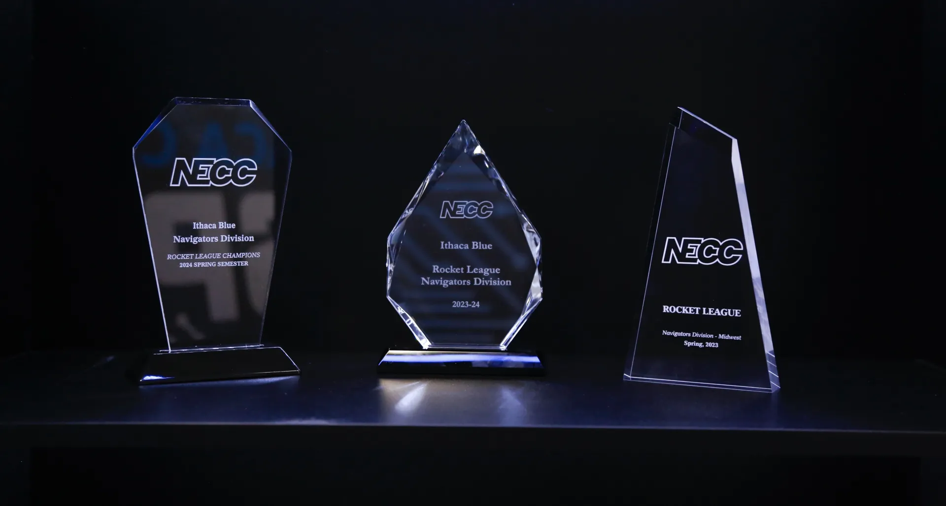 A trophy case with three NECC "Rocket League" trophies, including two national titles. 