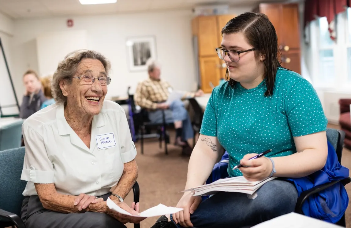 A female IC student sits with a smiling female resident. 