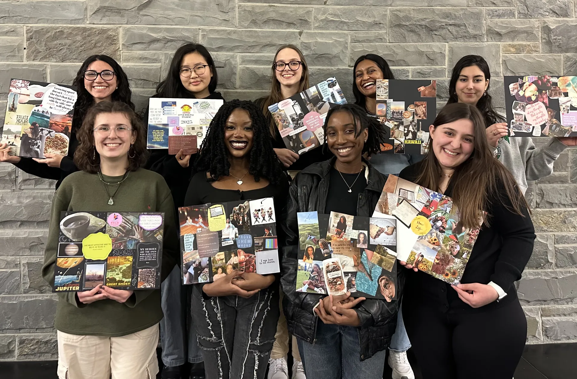 A group photo of nine women college students holding up vision boards. 