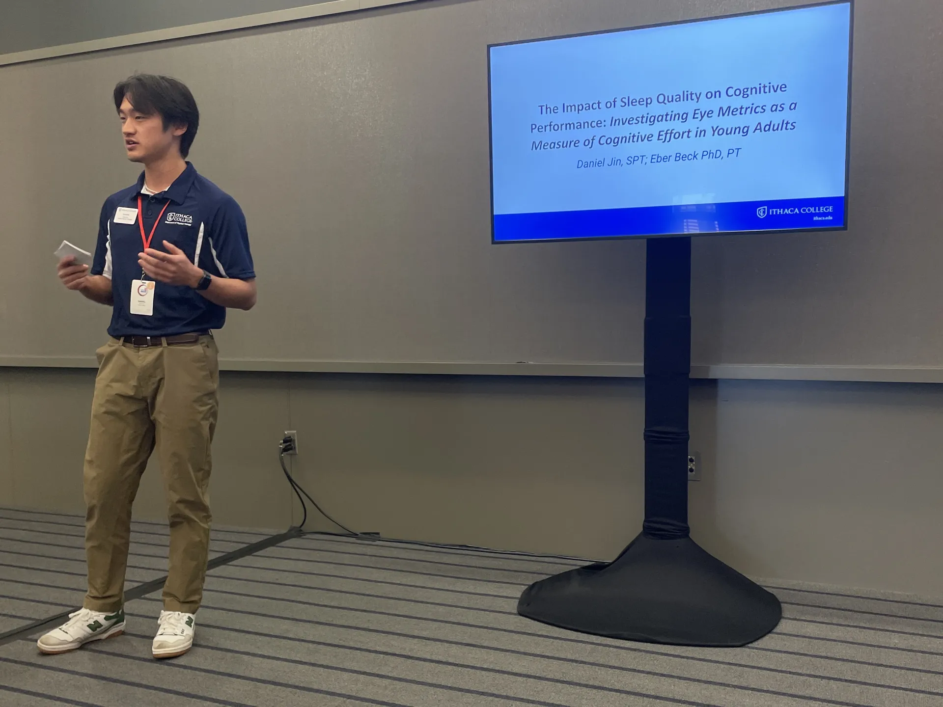 PT student stand in front of a TV displaying a scientific presentation