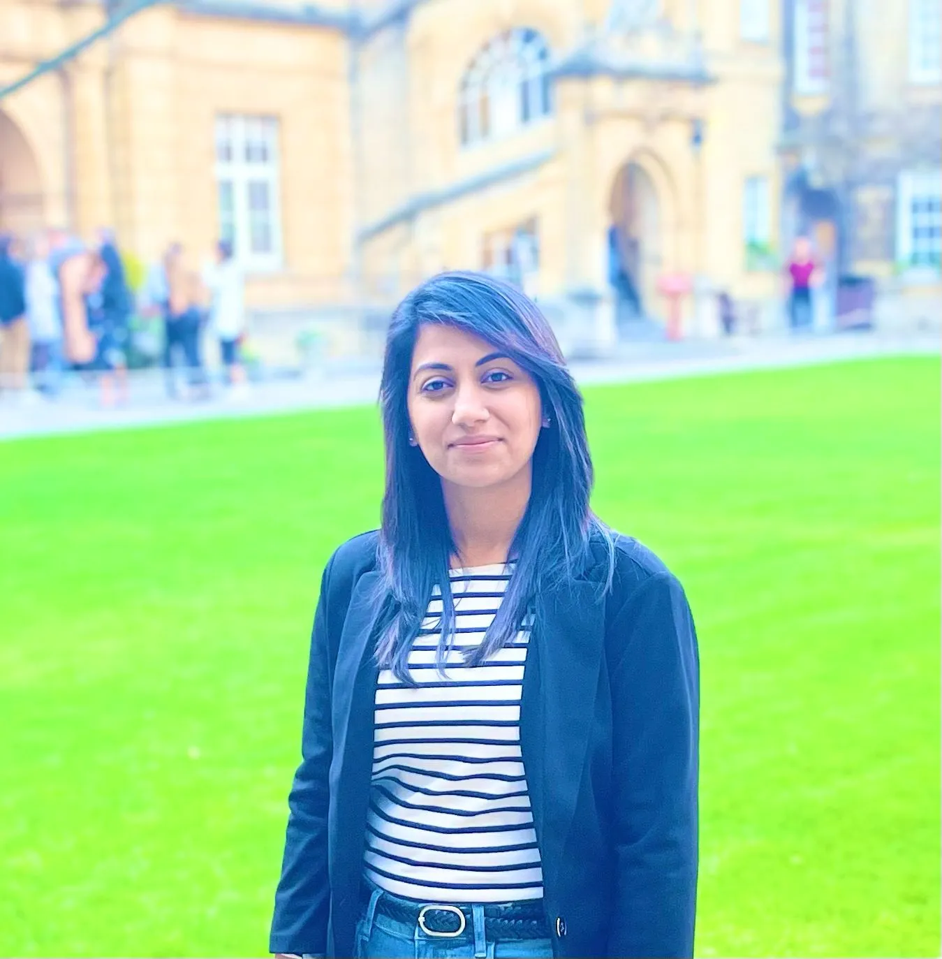 Standing infront of a lawn in a black blazer and hair down.