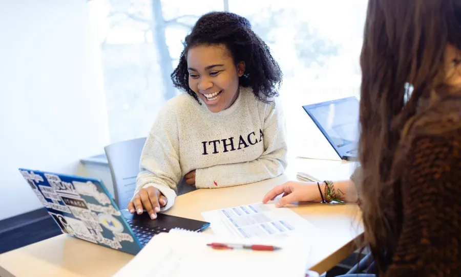 smiling female student looks at her open laptop