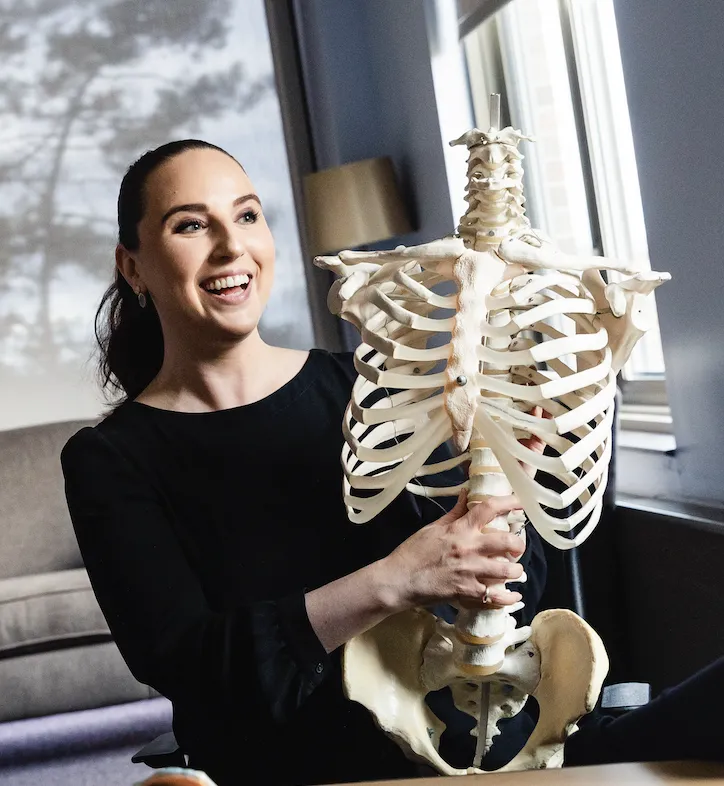 Woman smiling and holding a skeleton. 