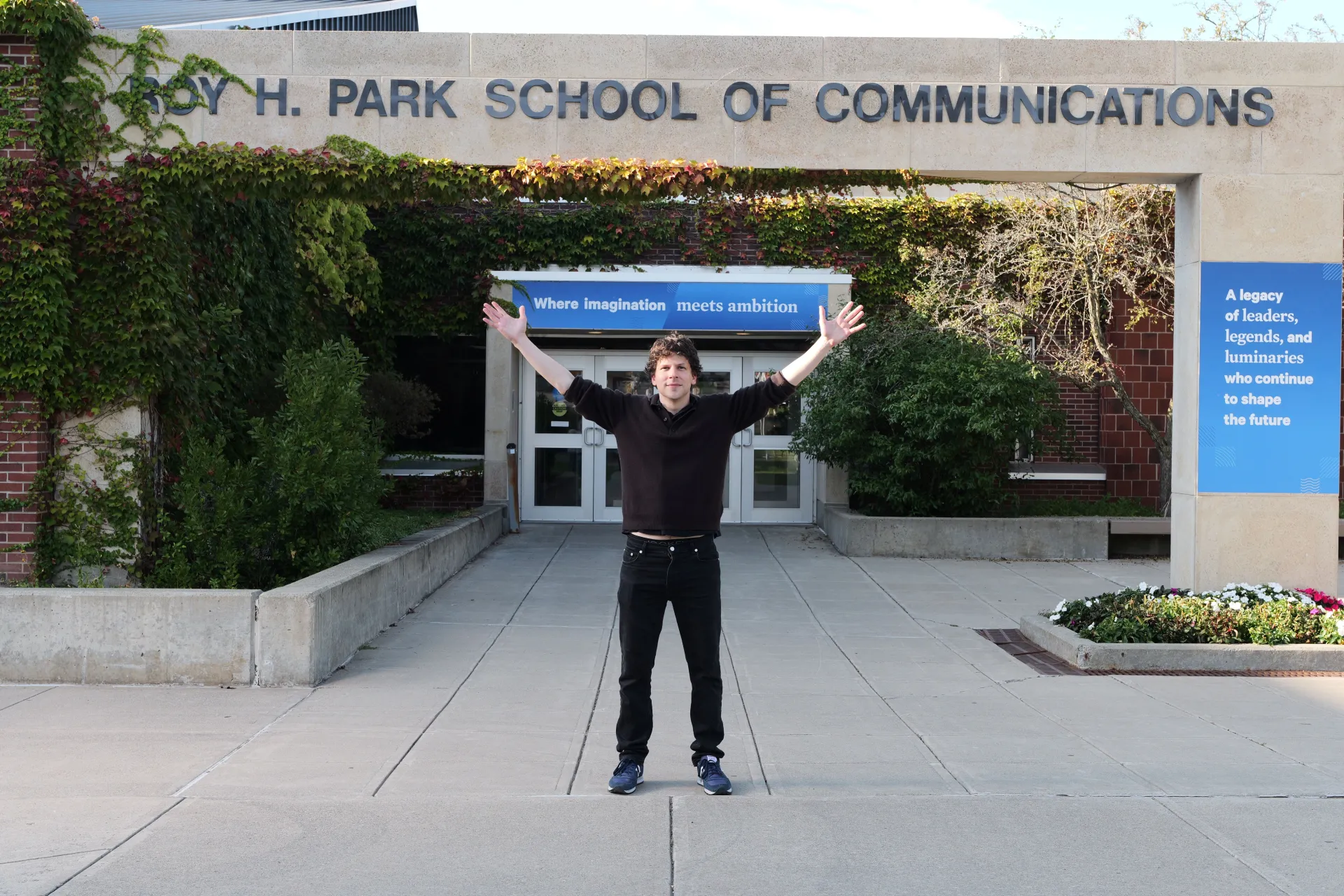 Actor Jesse Eisenberg stands at the entrance to the Roy H. Park School of Communications.