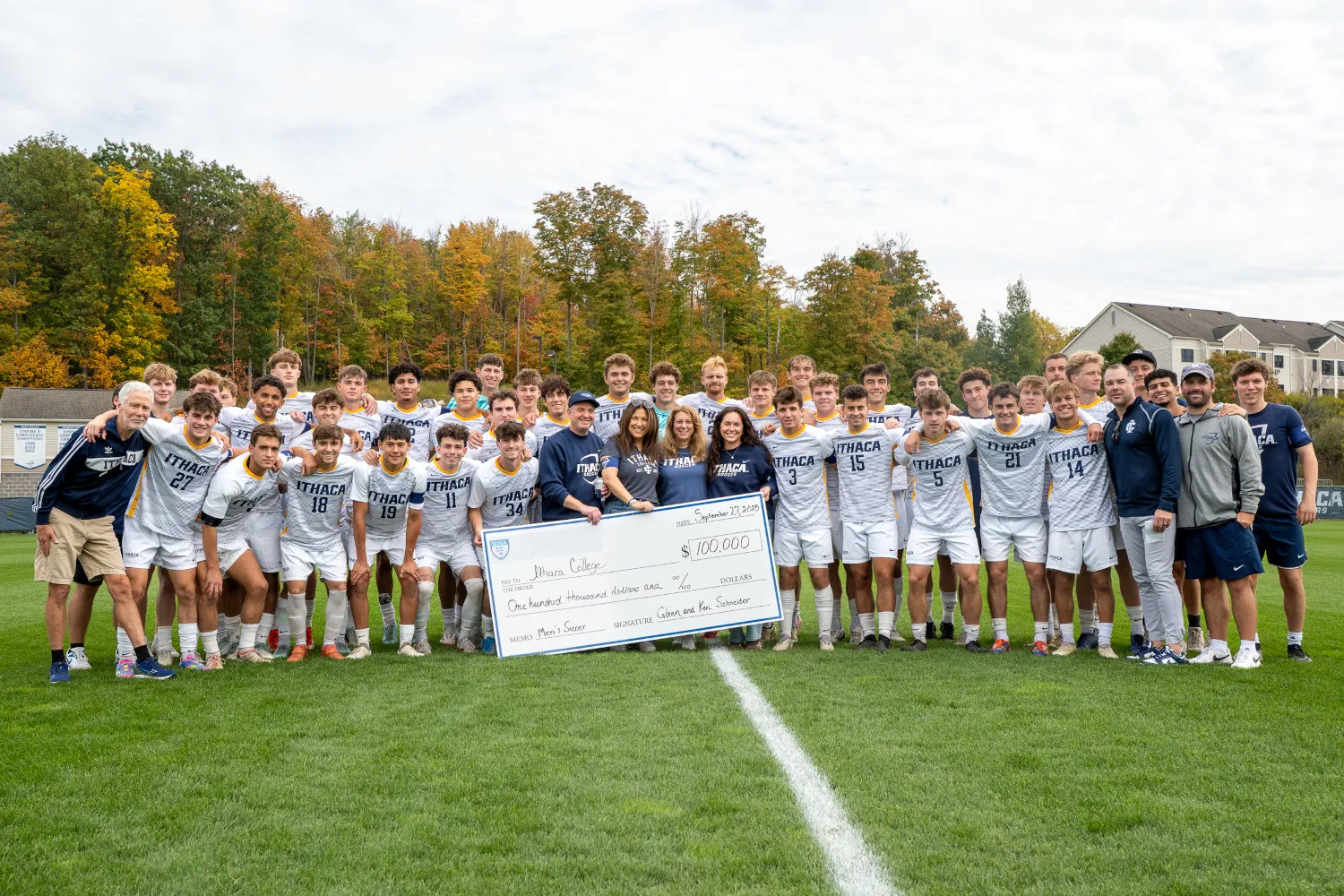 Soccer players and donors gather on a soccer pitch with a ceremonial check.