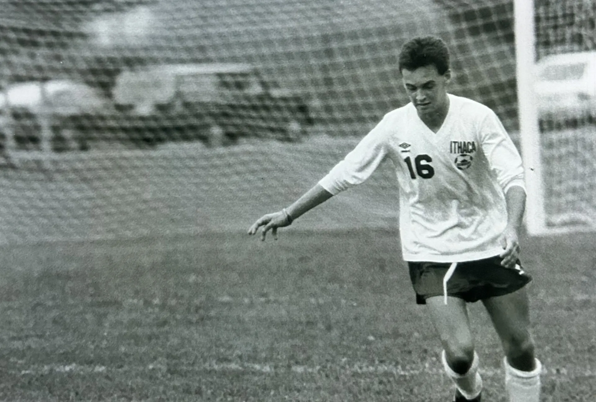 A college student plays soccer in a black and white photo.