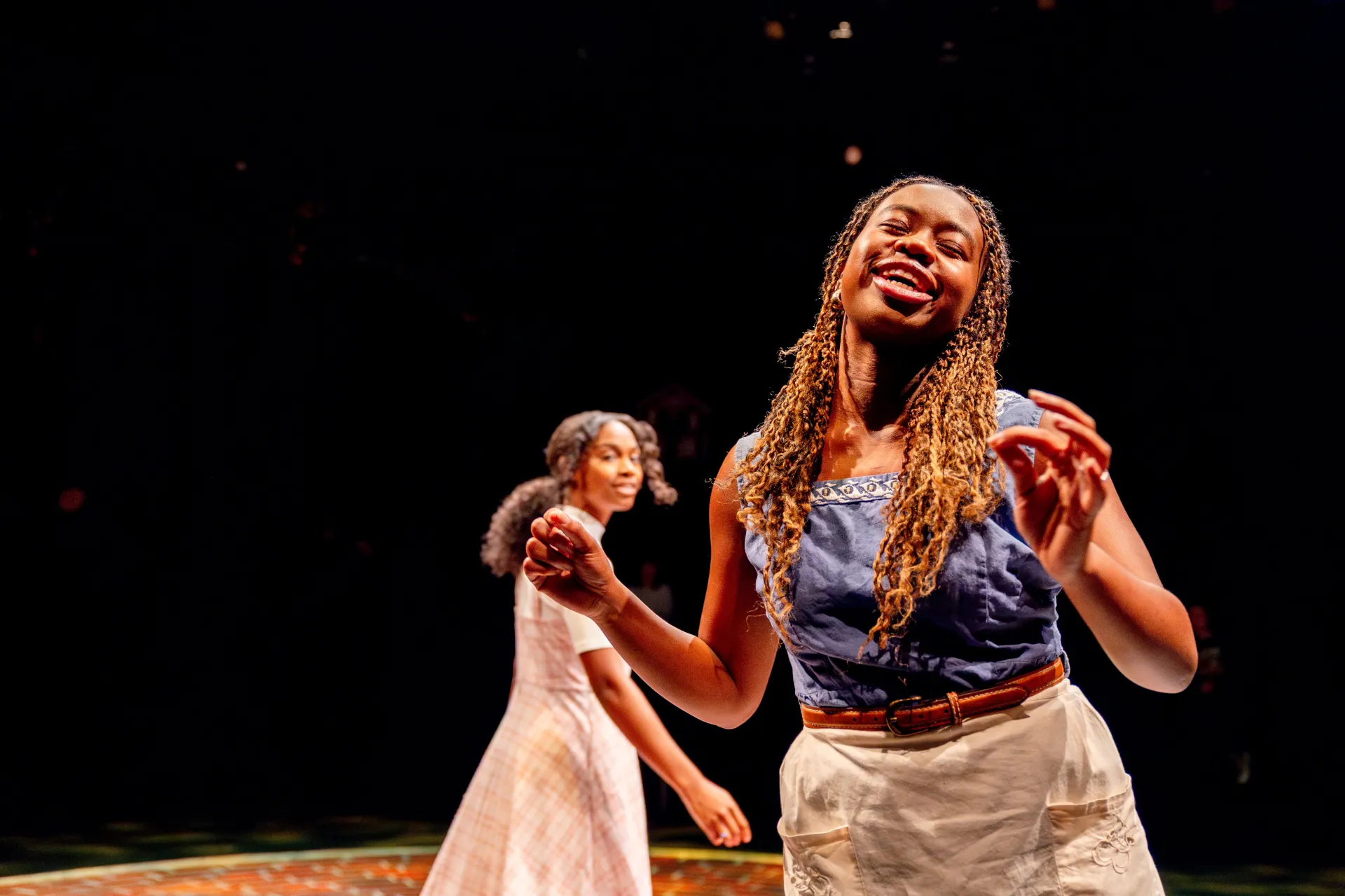 Two college students perform in a play onstage. 