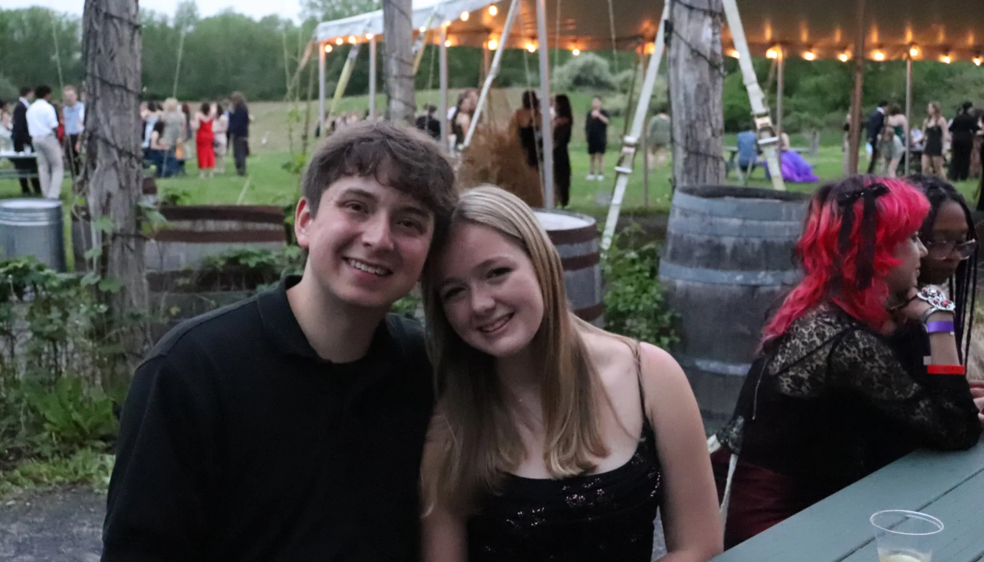 two students posing and smiling together at an outdoor picnic table