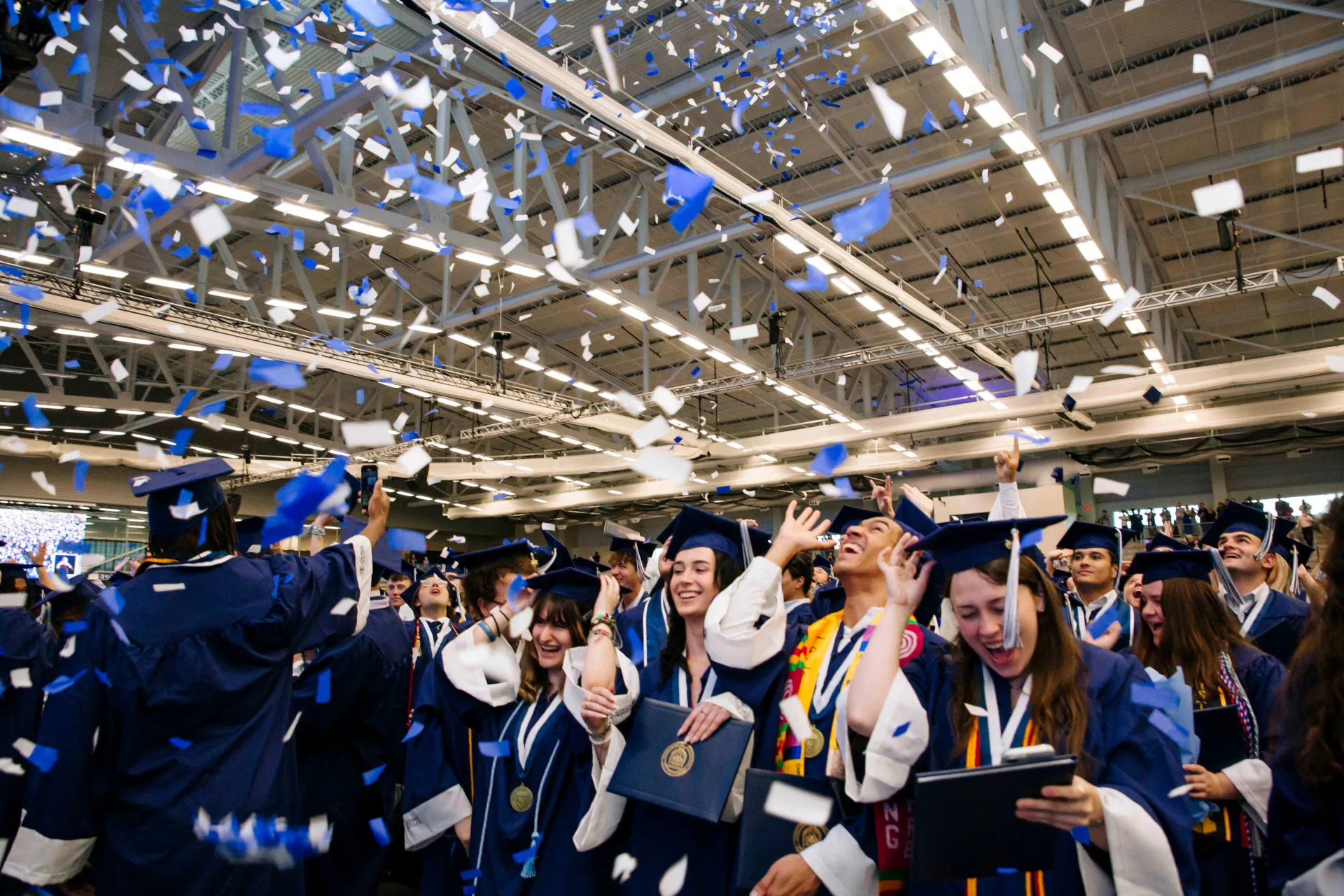 Graduates in gowns celebrate amidst confetti