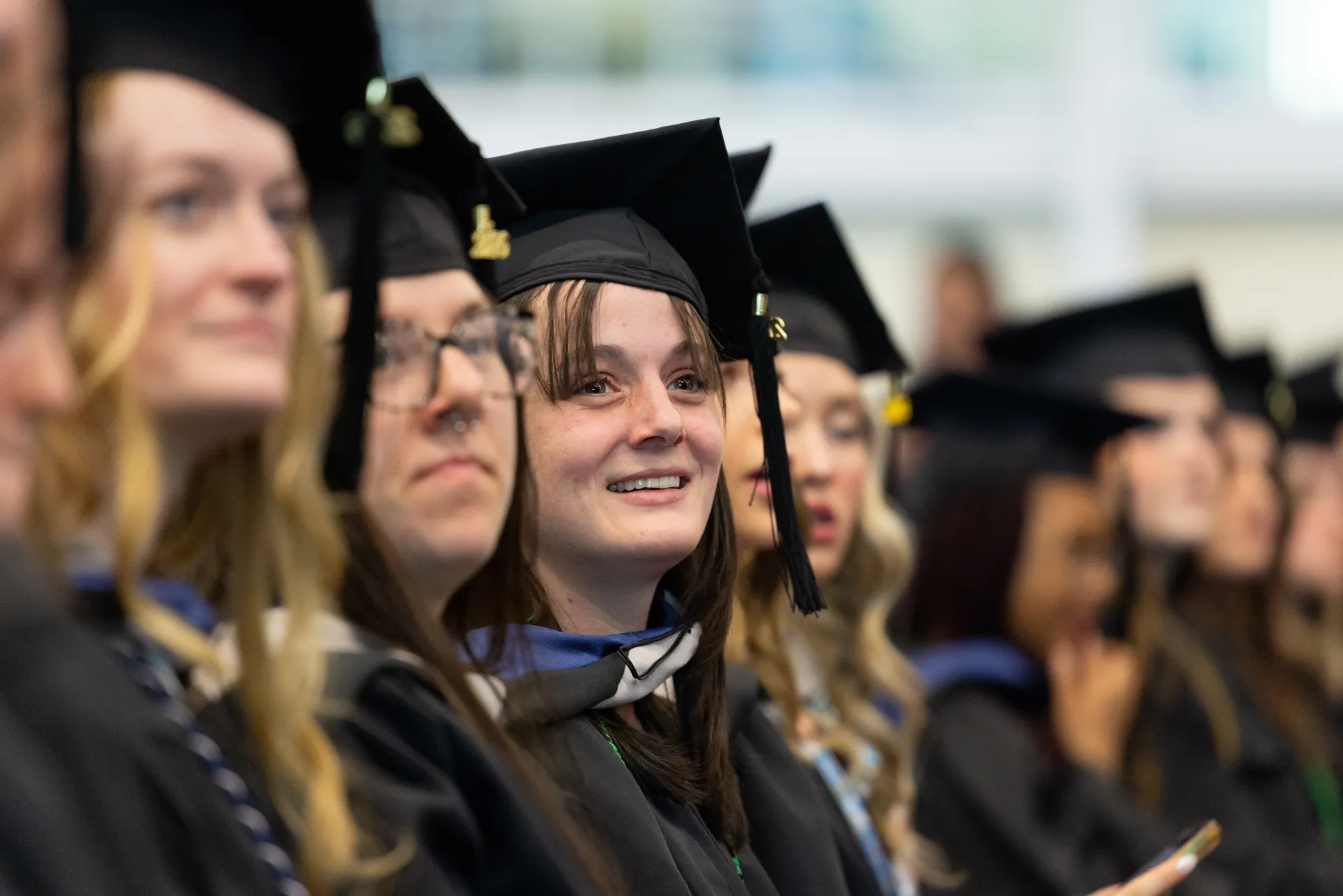 Graduate students at a commencement ceremony wear caps and gowns.