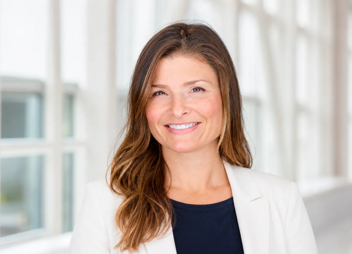 Casey Kendall, Deputy CIO, wearing a white blazer and navy blue top in a bright office setting