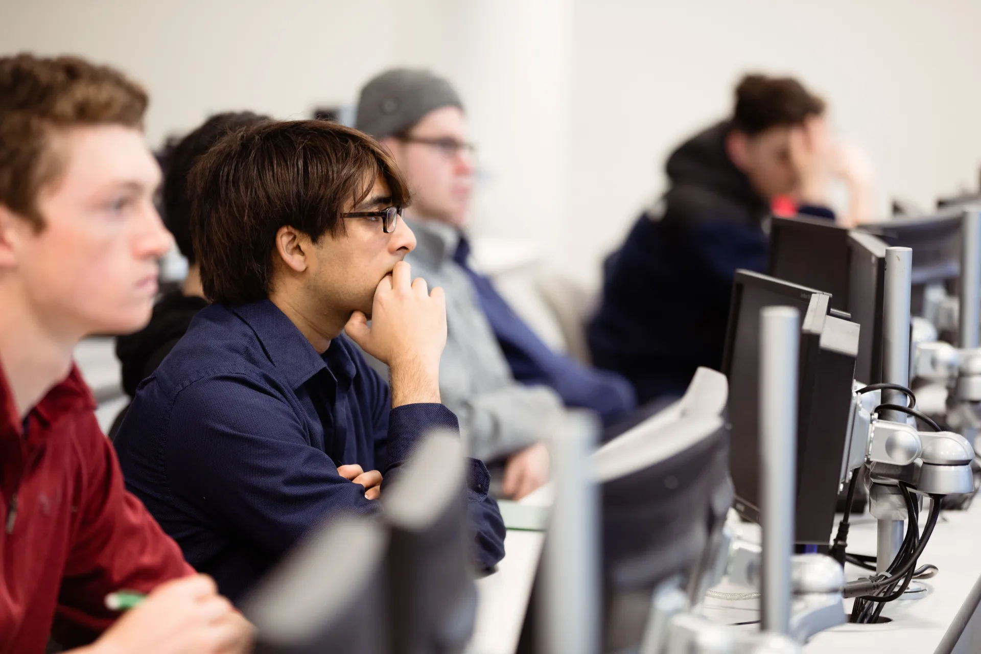 Students are seated in a row examining computer screens.