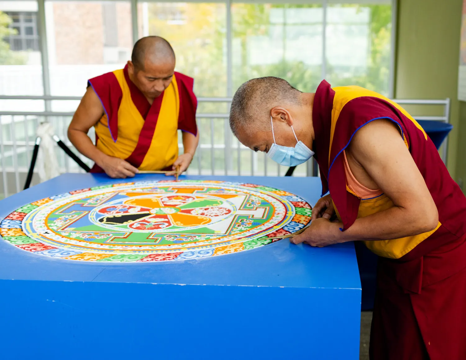 Two Tibetan Bhuddhist monks construct a sand mandala.