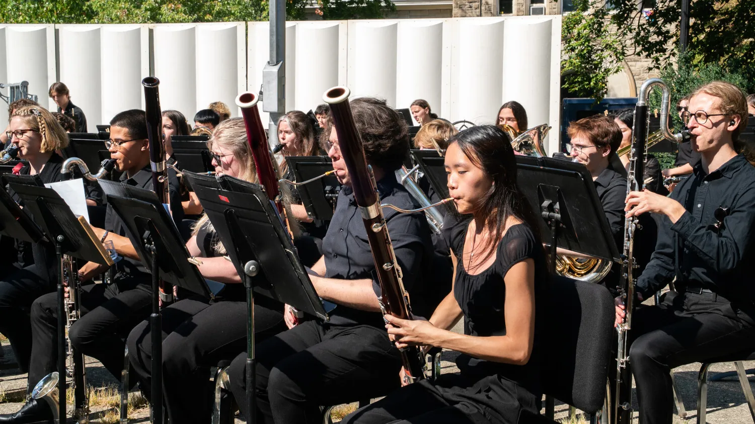Student woodwind musicians perform at an outdoor concert.