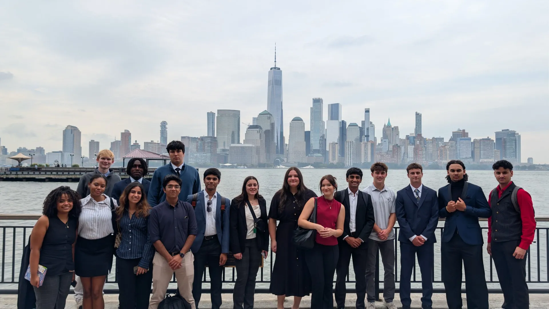 A group of 15 students are standing in front of the skyline of New York City