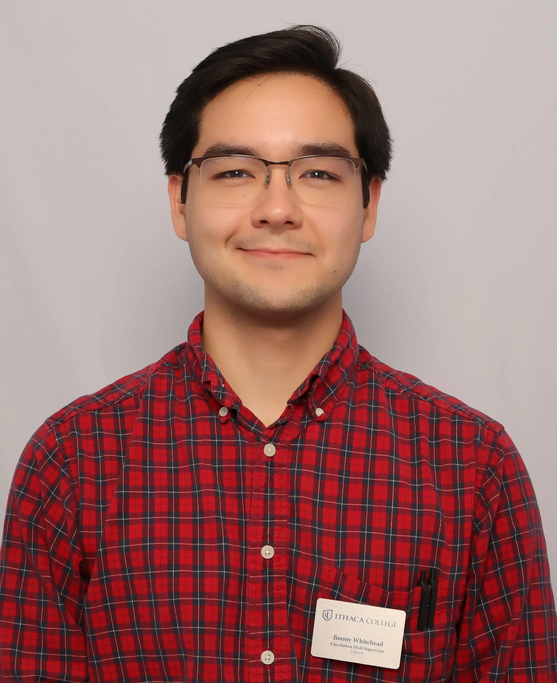 Headshot photograph of Jimmy Whitehead, smiling, in a plaid shirt