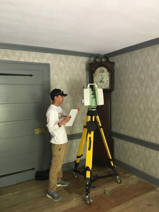 A man standing next to a 3D scanner inside a house