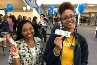 Two young women holding tickets
