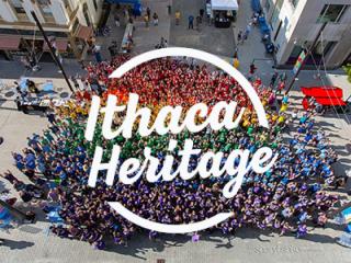 Large group of people wearing tshirts in different colors of the rainbow, with Ithaca Heritage logo 