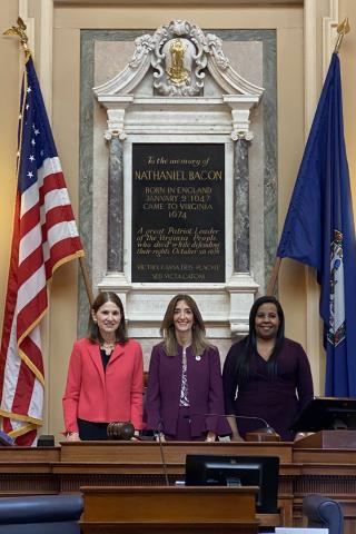 three women in front of a plaque