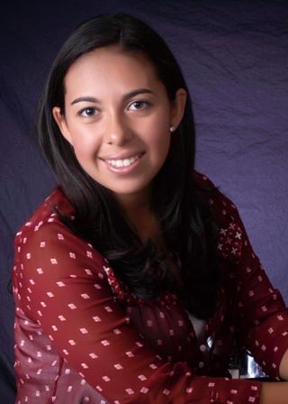 This is a photo of Keanna Morales. Keanna is wearing a maroon long sleeve shirt with yellow dots. Keanna is smiling at the camera.