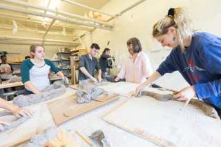 Students working around a table sculpting clay
