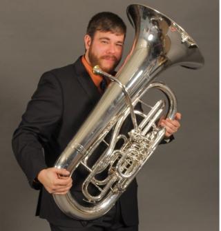 Person in suit standing holding tuba