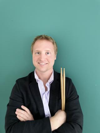 Headshot of a man holding drumsticks