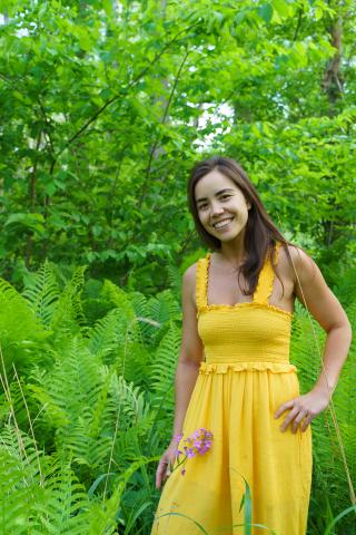 Person smiling while standing in outdoor greenery