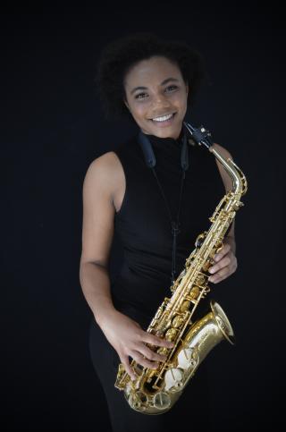Person smiling while holding saxophone