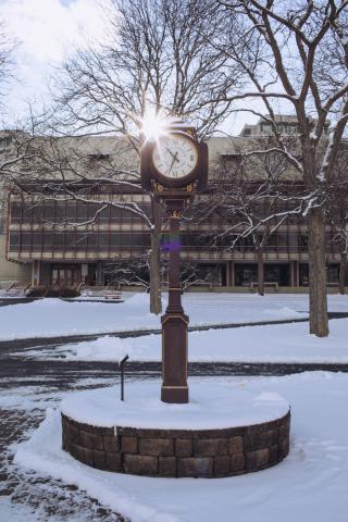 A winter photo of the clock in the middle of the academic quad, with snow on the ground.