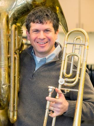 Man with trombone and tuba smiling