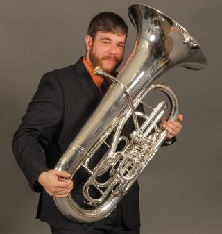 Man in a suit holding a tuba