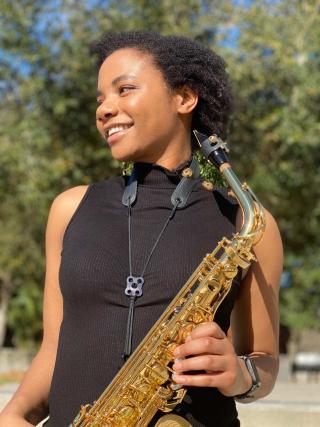 Woman smiling holding a saxophone