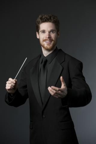 Man in a black suit with a baton