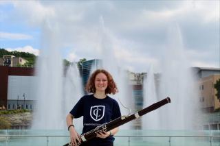 Woman holding a bassoon in front of fountains