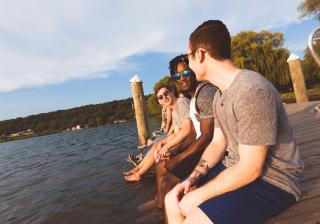 a group of students sits on a dock overlooking the lake
