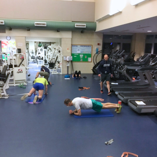 4 runners utilizing the fitness floor equipment to stretch and perform conditioning exercises.