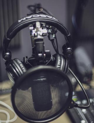 headphones hanging on podcast mic behind the pop filter
