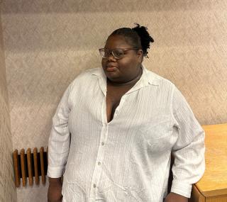 Image of Ashanti Ford. Ashanti is wearing a white button down shirt and glasses and is looking directly at the camera.