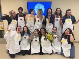 13 students wearing painting aprons