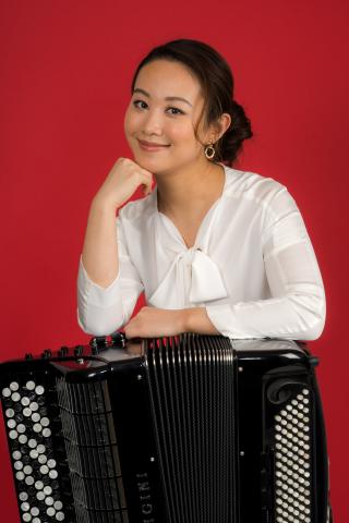A woman stands with an accordion